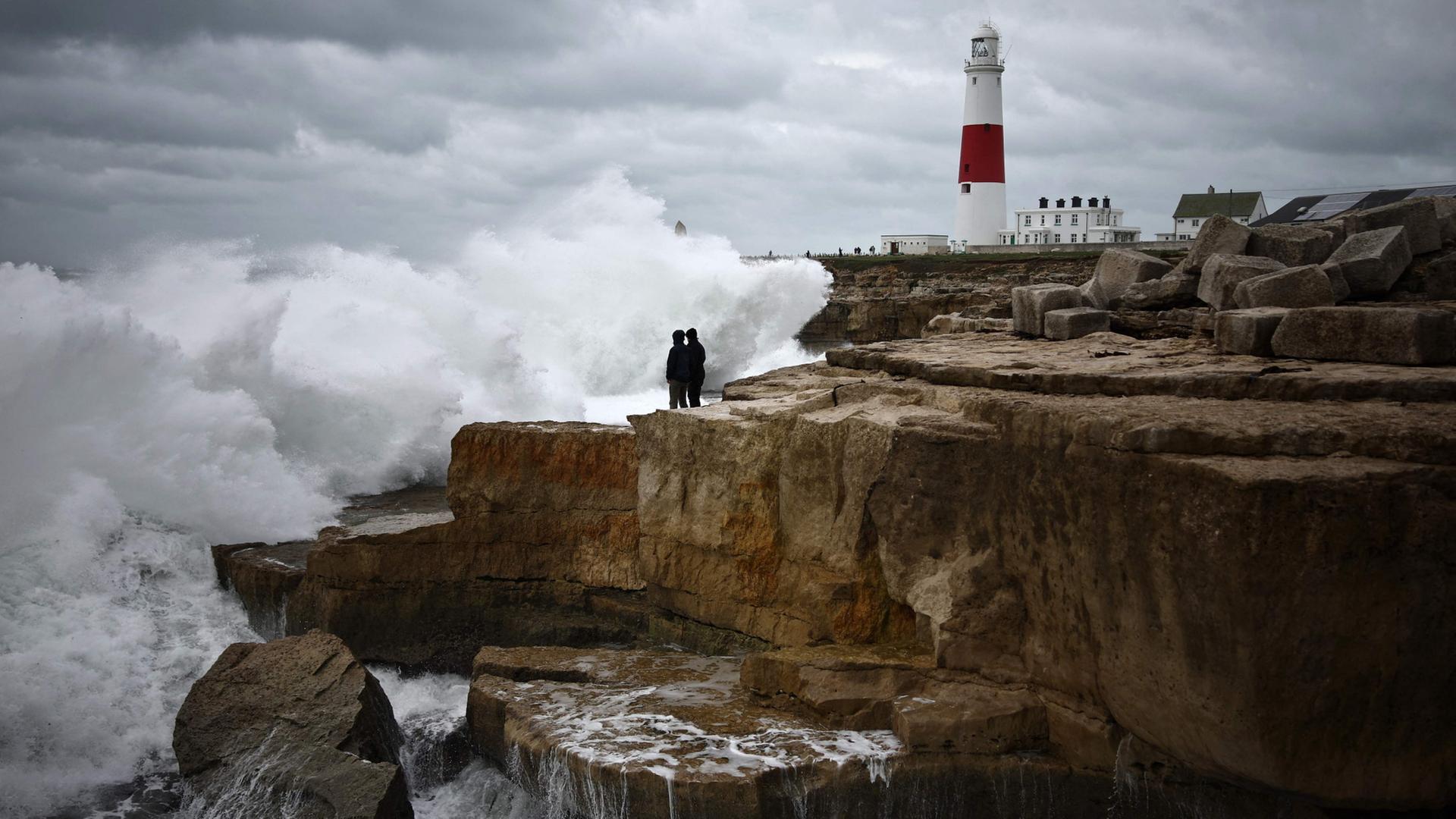 Menschen stehen auf Felsen, wÃ¤hrend sich in der NÃ¤he des Leuchtturms von Portland Bill in Portland, SÃ¼dengland, am 23. Oktober 2026 die Wellen breche | AFP