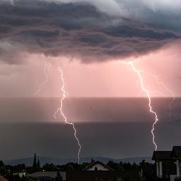 Zwei Blitze schlagen in der Dämmerung über einem Ort ein.