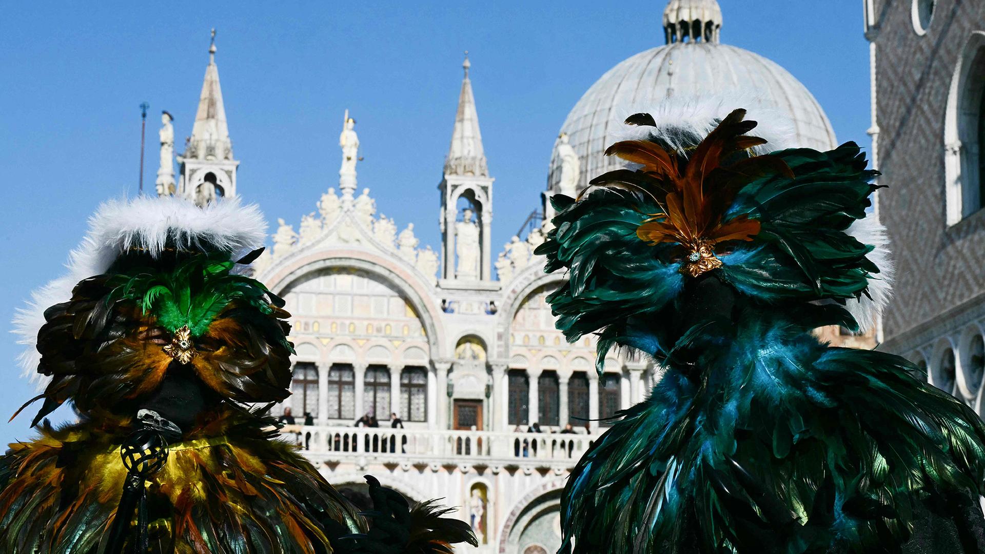 Zwei mit Federn geschmÃ¼ckte Personen nehmen am Karneval in Venedig teil. | AFP