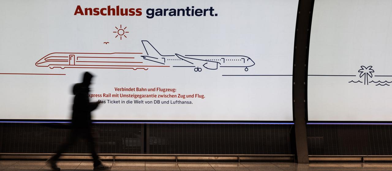 Passagier läuft am Flughafen Frankfurt an Anzeigetafel vorbei
