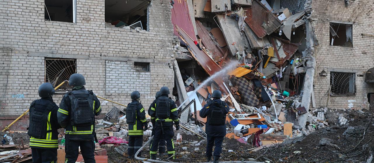Nach dem Einschlag einer russischen Rakete in ein Wohnheim in Saporischschja, Ukraine, kümmern sich Rettungskräfte um den Tatort.