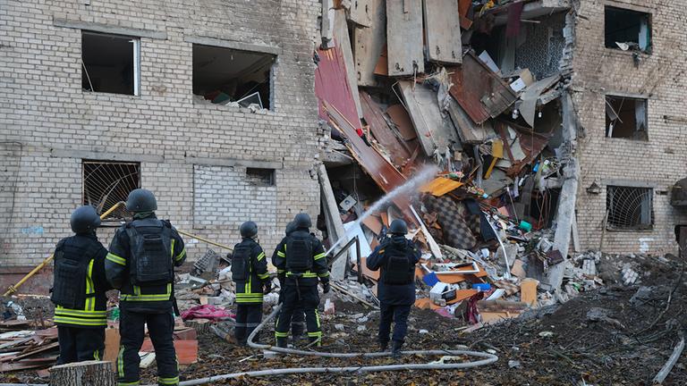 Nach dem Einschlag einer russischen Rakete in ein Wohnheim in Saporischschja, Ukraine, kümmern sich Rettungskräfte um den Tatort.