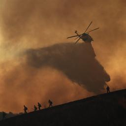 Ein Hubschrauber wirft Wasser auf ein Feuer in Los Angeles.