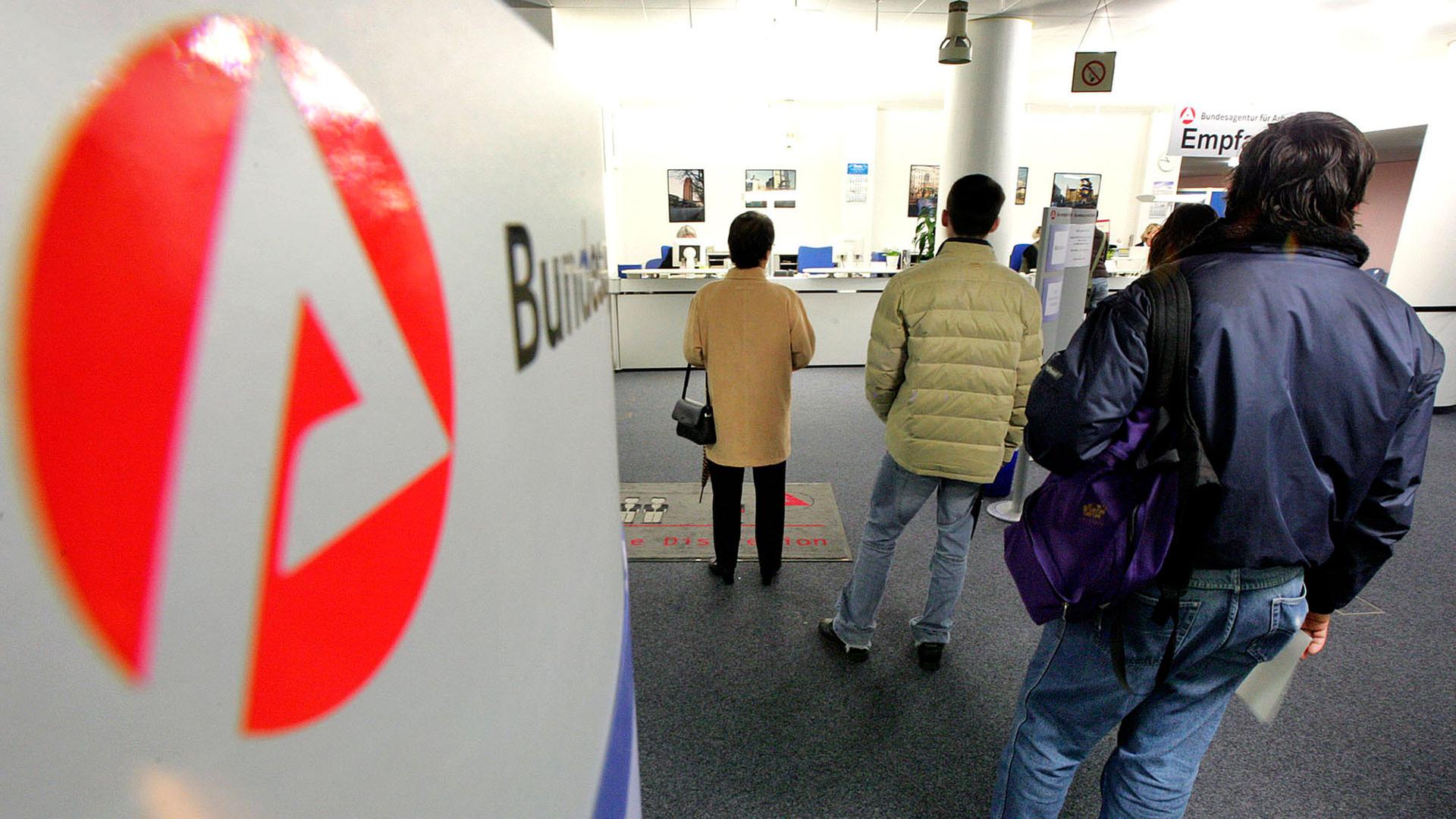 Menschen stehen in einem Jobcenter der Bundesagentur für Arbeit in einer Schlange. | picture alliance / ASSOCIATED PR