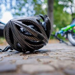 Ein Fahrradhelm und ein Fahrrad liegen nach einem Unfall auf der Straße.
