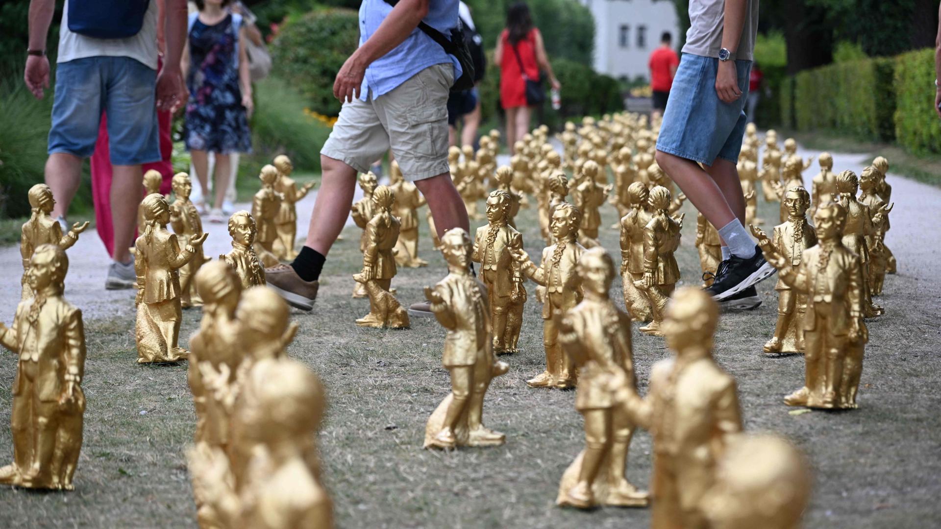 Besucher schlendern im Mirabellgarten in Salzburg an einer Kunstinstallation namens 