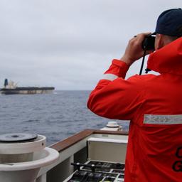 Ein Beamter der US-Küstenwache beibachtet das Schiff Marinera (ehemals Bella 1) durch ein Fernglas.