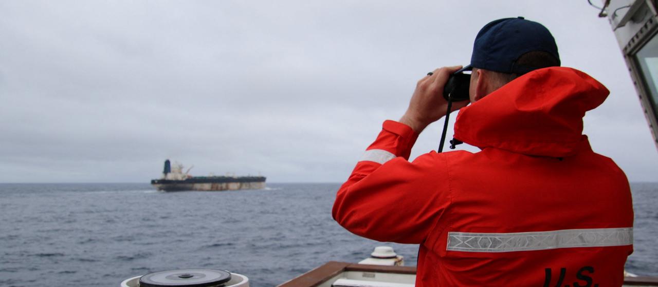 Ein Beamter der US-Küstenwache beibachtet das Schiff Marinera (ehemals Bella 1) durch ein Fernglas.