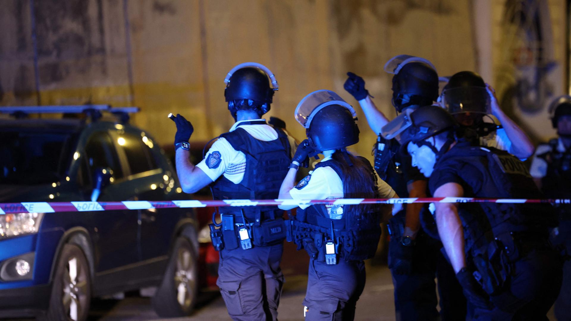 Uniformierte Polizisten hinter einer Absperrung auf einer Straße. | AFP