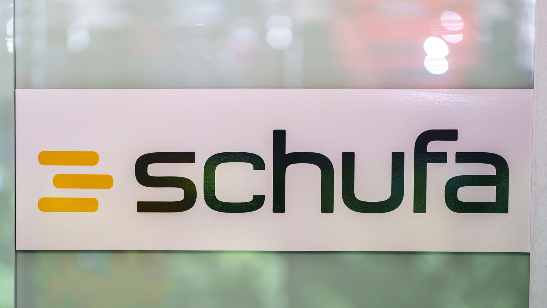 Das Schufa-Logo steht auf einer Glastür. | Andreas Arnold/dpa