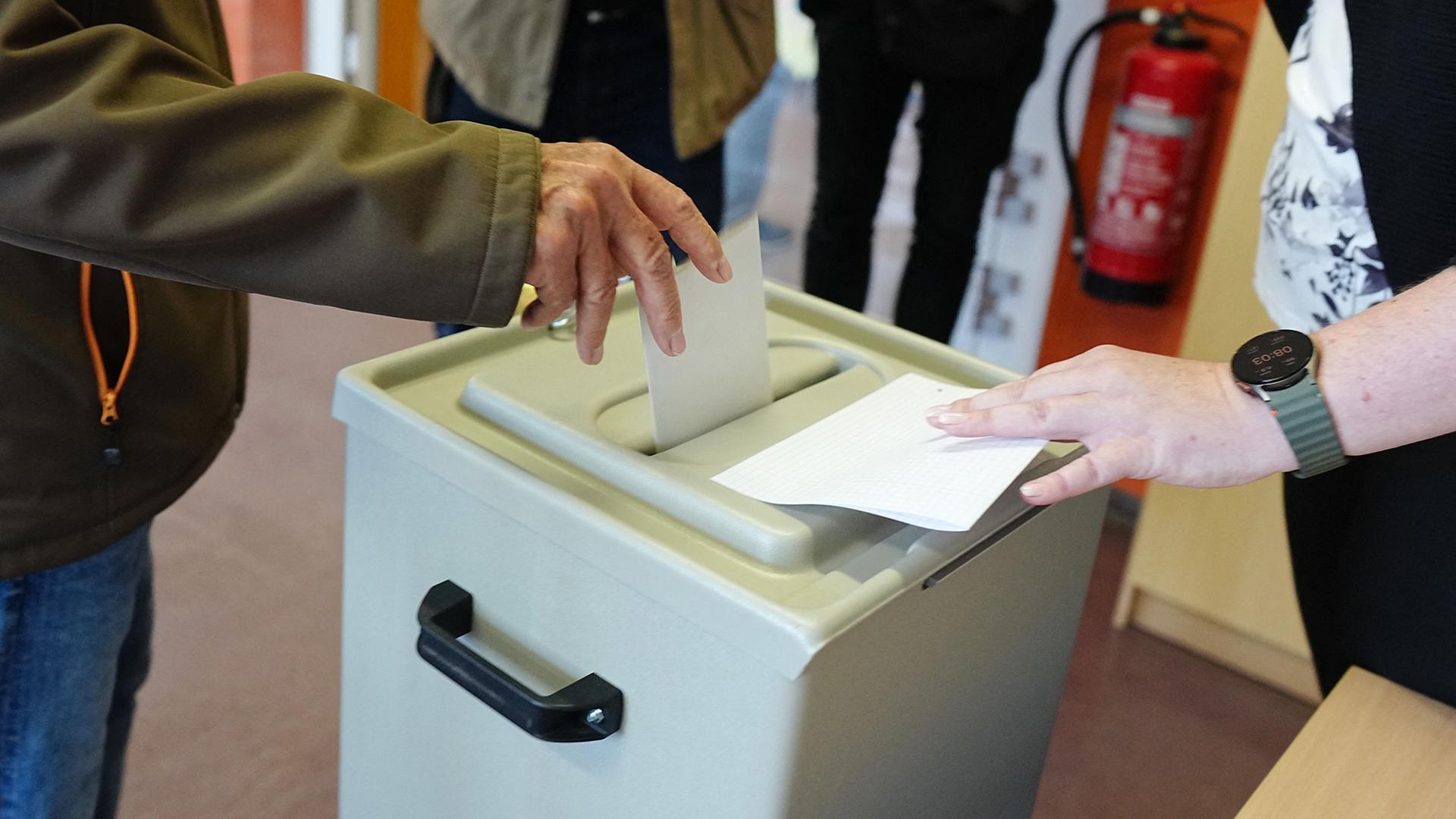 Ein Wähler wirft seinen gefalteten Stimmzettel in die Wahlurne in einem Wahllokal. | Kay Nietfeld/dpa