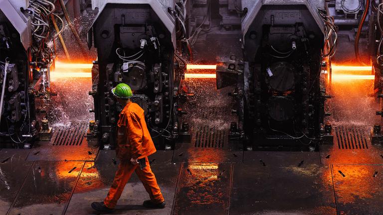 Ein Mitarbeiter der Badischen Stahlwerke GmbH (BSW) geht durch das Walzwerk der Firma.