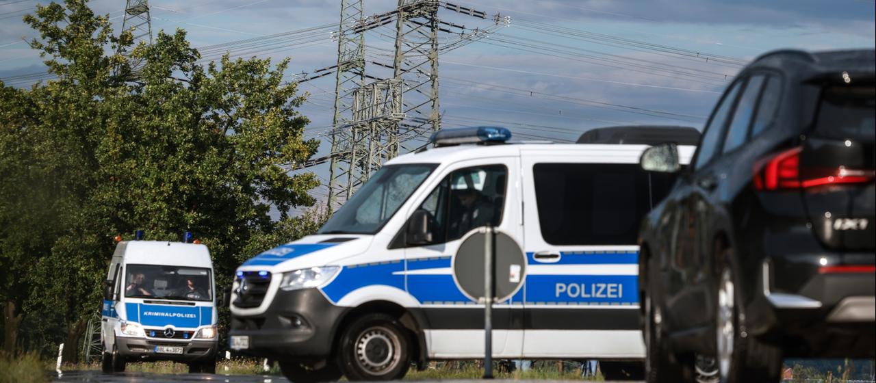 Polizeifahrzeuge stehen vor Hochspannungsleitungen in Turnow-Preilack in Brandenburg