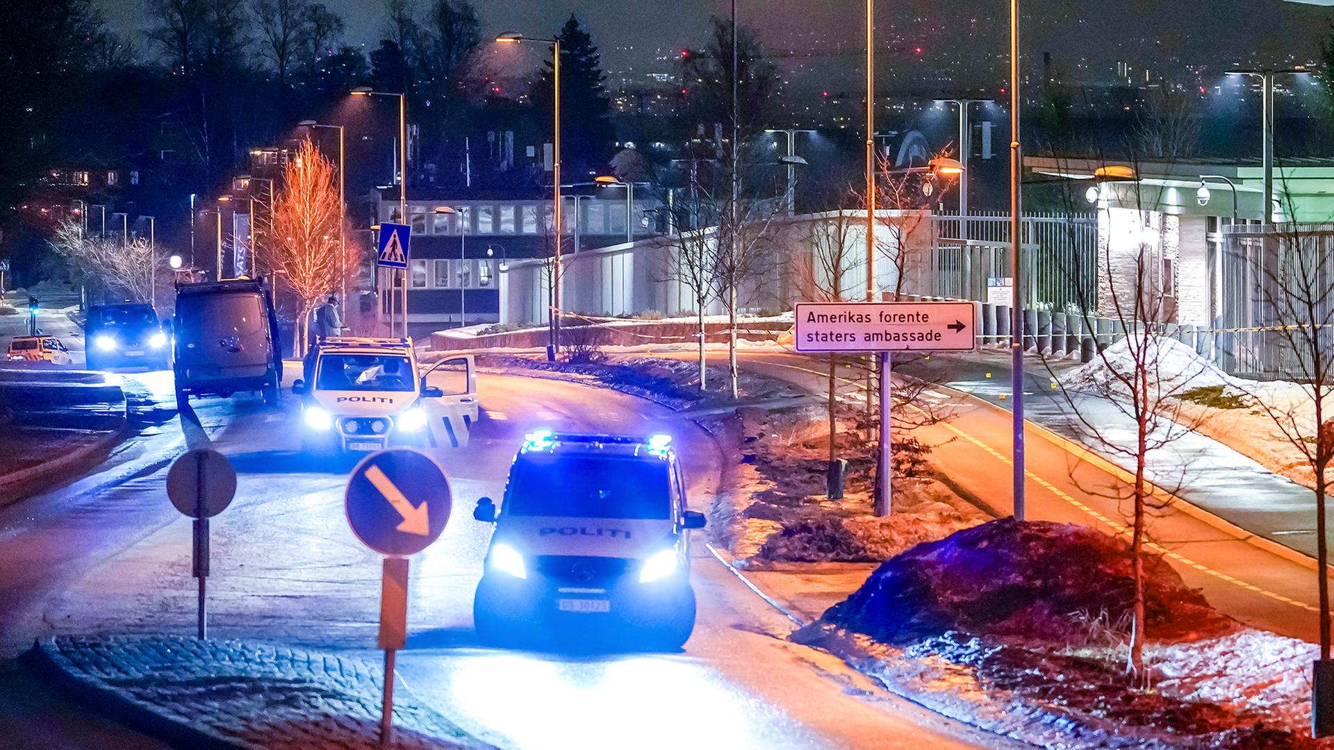 Mehrere Polizeifahrzeuge stehen mit eingeschaltetem Blaulicht nachts auf einer StraÃe vor der US-Botschaft in Oslo. | EPA