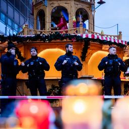 Sachsen-Anhalt, Magdeburg: Polizisten sichern den Weihnachtsmarkt, wobei Kerzen vor ihnen brennen.