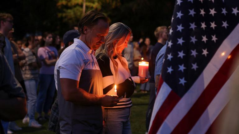 Zwei Menschen stehen mit Kerzen neben einer US-Flagge in Utah