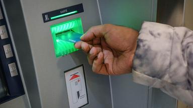 Eine Person steckt Ihre Girocard in einen Geldautomat.