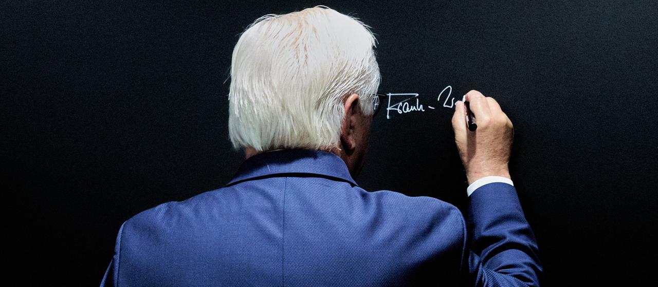 Frank-Walter Steinmeier schreibt seinen Namen an eine Tafel.
