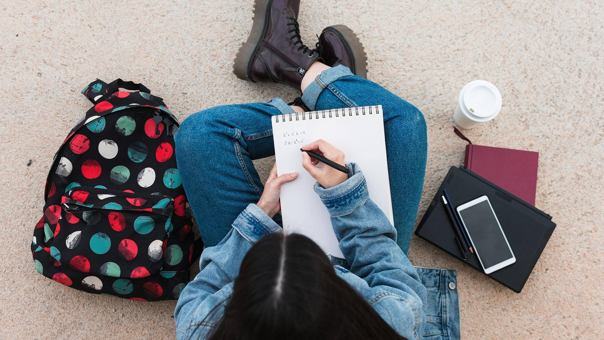 Draufsicht, auf eine Studentin die etwas schreibt. | imago images/Cavan Images