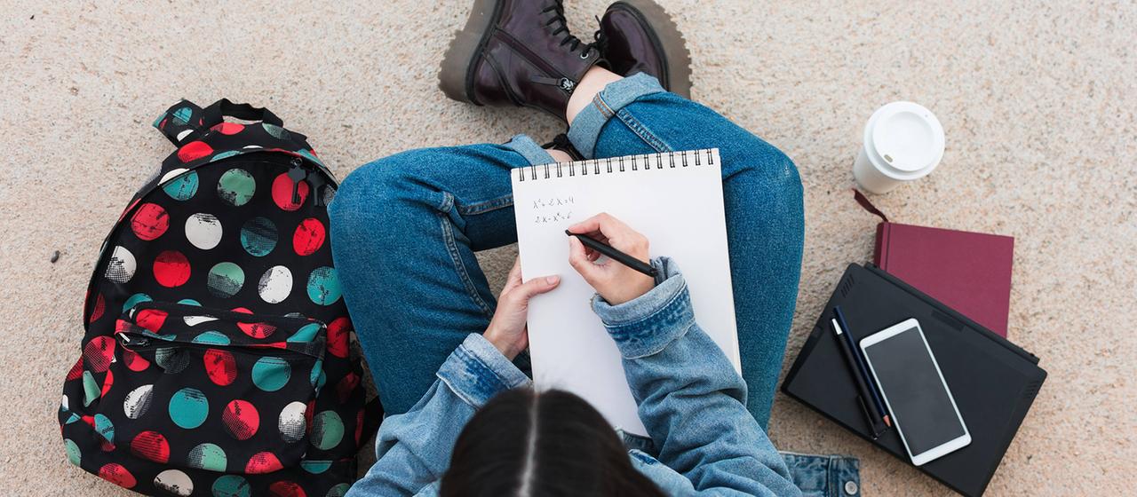 Draufsicht, auf eine Studentin die etwas schreibt.