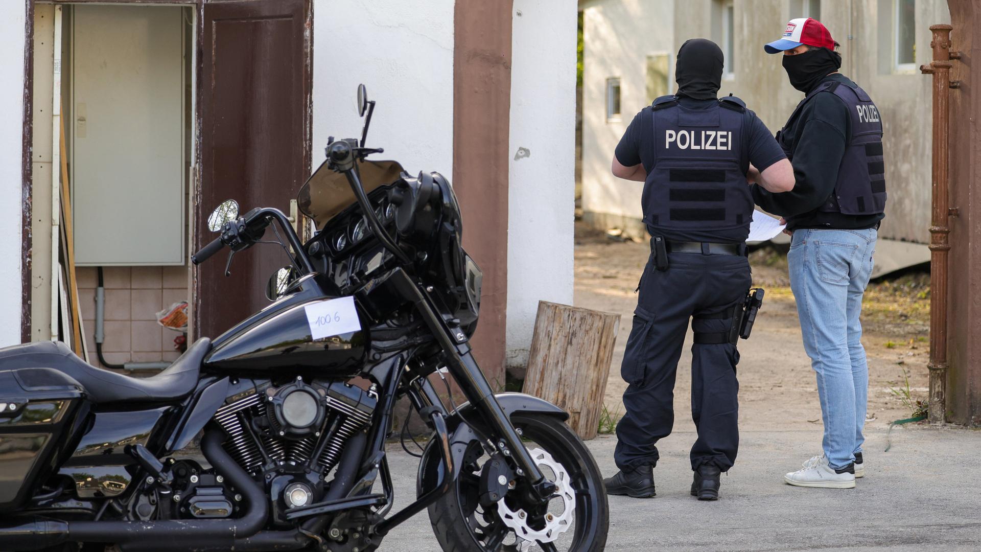 Ein Motorrad, das im Rahmen einer Razzia gegen die Rockergruppe Hells Angels von der Polizei beschlagnahmt wurde, steht vor einem Haus | dpa / Christoph Reichwein