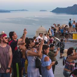 Touristen fotografieren den Sonnenuntergang nahe Oia auf Santorini (Griechenland)