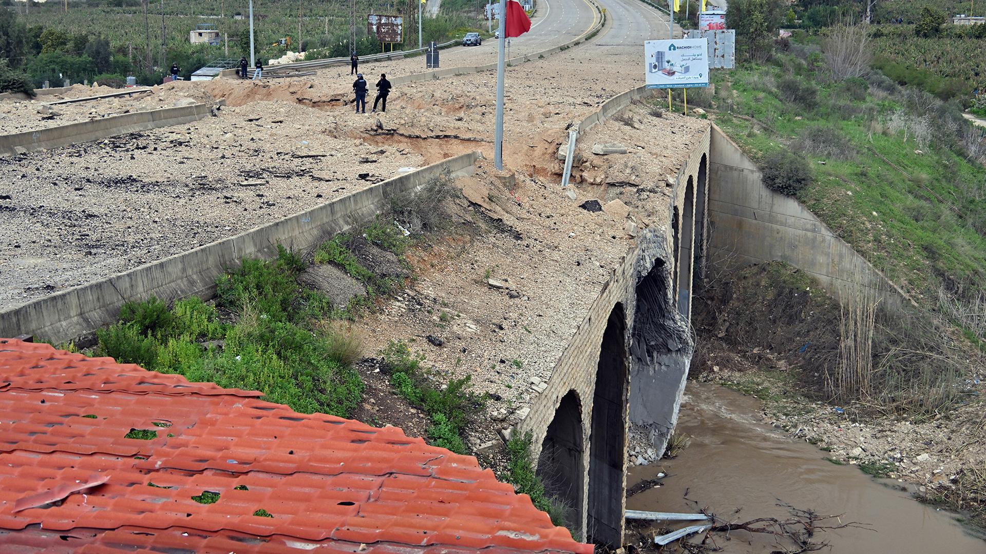 Menschen stehen auf einer zerstörten Brücke. | EPA