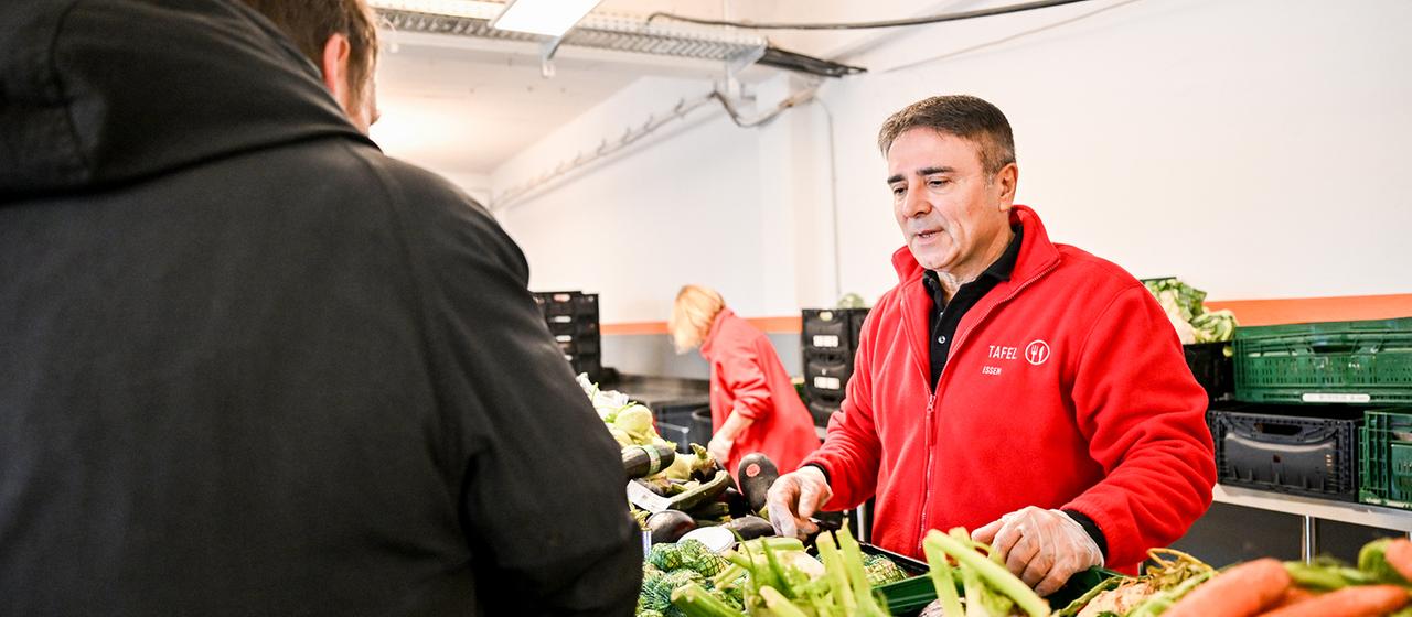Ein Mann verteilt Lebensmittel der Essener Tafel an Gäste.