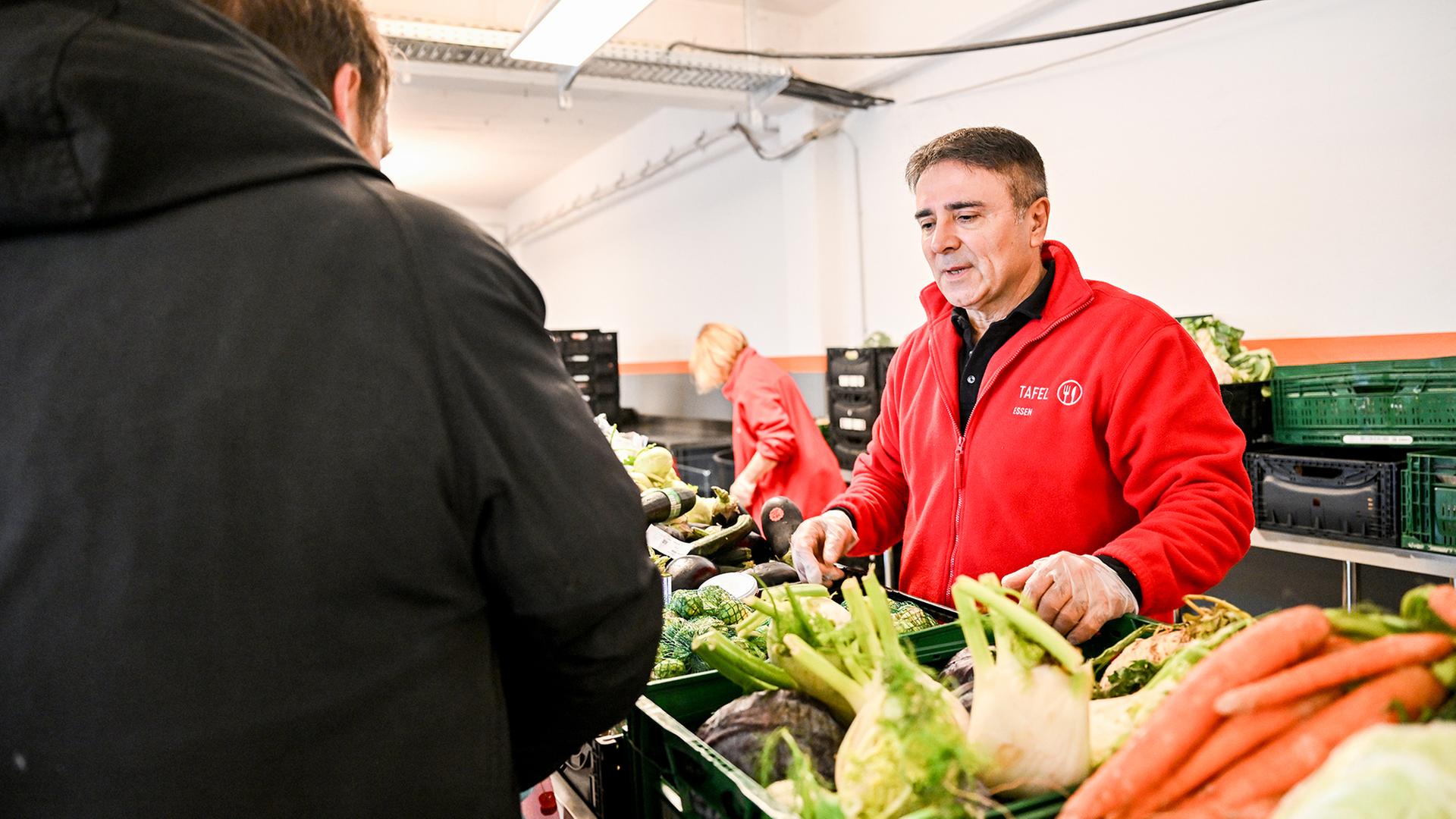 Ein Mann verteilt Lebensmittel der Essener Tafel an Gäste. | IMAGO/Funke Foto Services