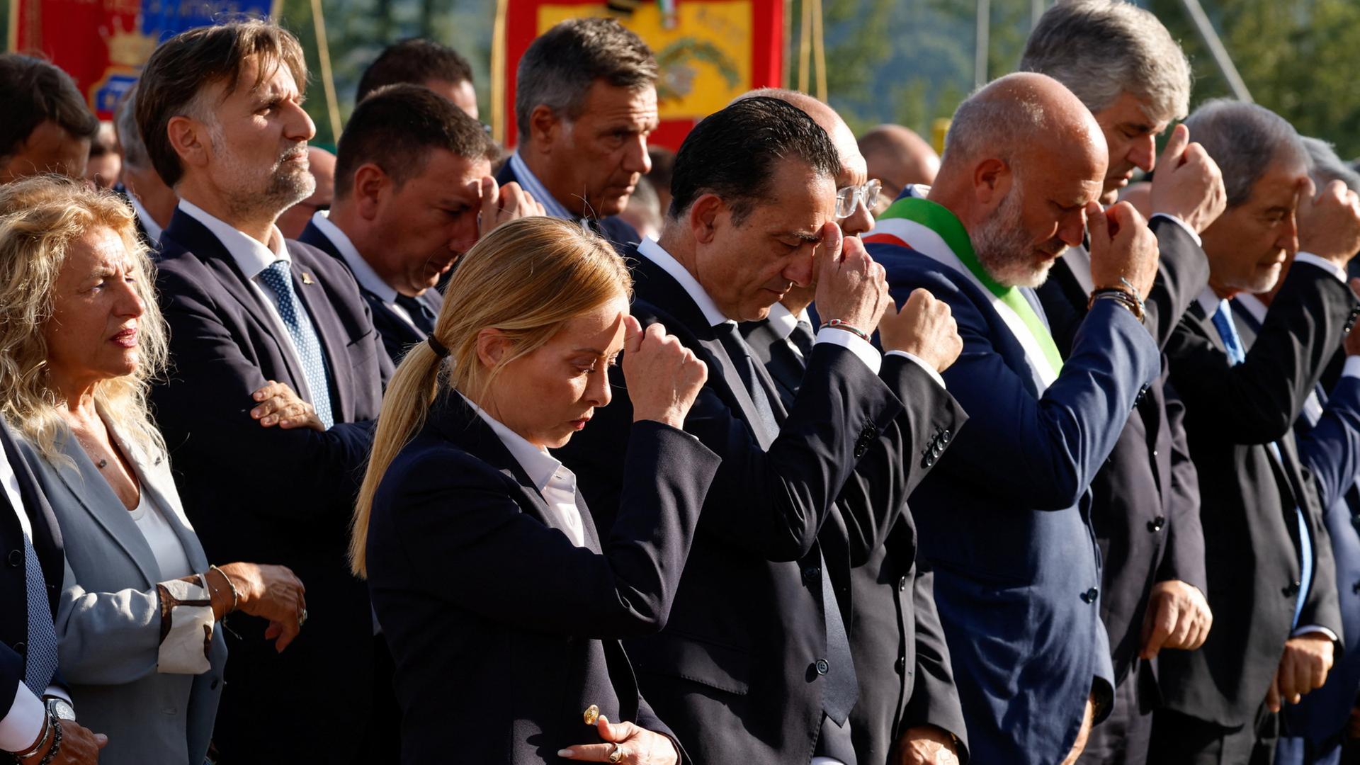 Giorgia Meloni und andere Personen in schwarz gekleidet mit gesenkten Köpfen | REUTERS