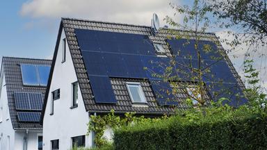 Solarpanele und Solarthermie auf dem Dach eines Einfamilienhaus.