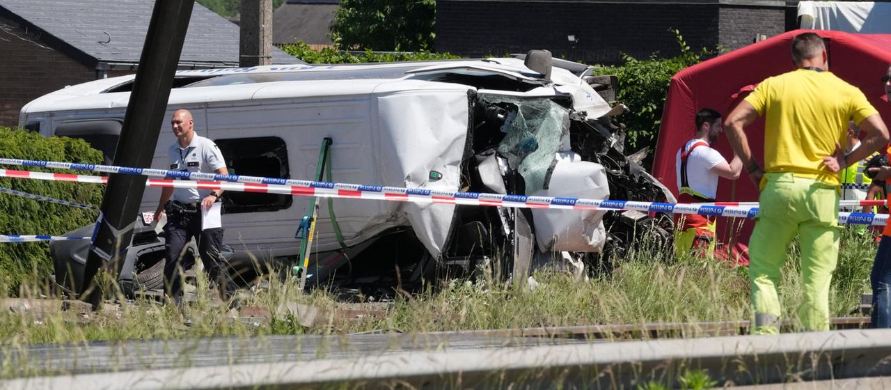 Rettungskräfte sind an einem Bahnübergang in Buggenhout, Belgien an einem verunglückten Schulbus im Einsatz.