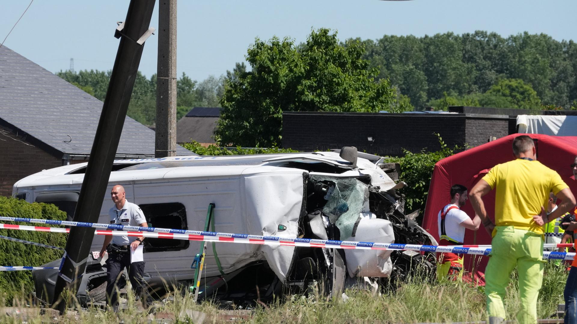 Rettungskräfte sind an einem Bahnübergang in Buggenhout, Belgien an einem verunglückten Schulbus im Einsatz. | AP Photo/Marius Burgelman