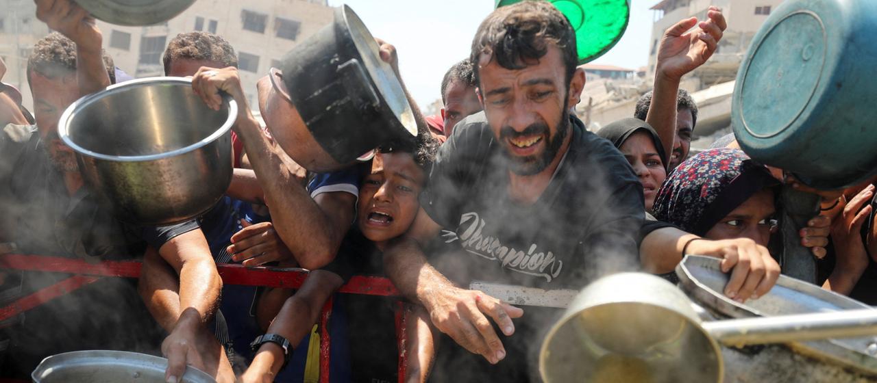 Menschen im Gazastreifen warten auf die Ausgabe von Nahrungsmitteln.