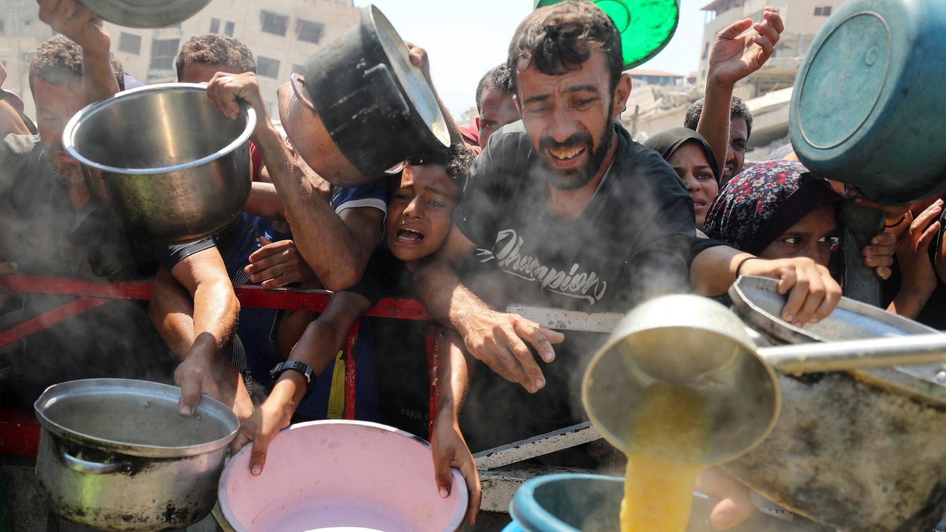 Menschen im Gazastreifen warten auf die Ausgabe von Nahrungsmitteln. | REUTERS