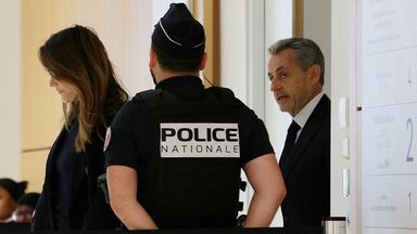 Nicolas Sarkozy verlässt einen Gerichtssaal, im Vordergrund ein Polizist.
