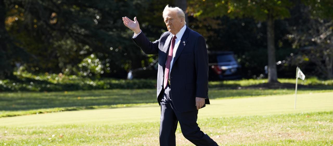 Donald Trump geht über eine grüne Wiese.