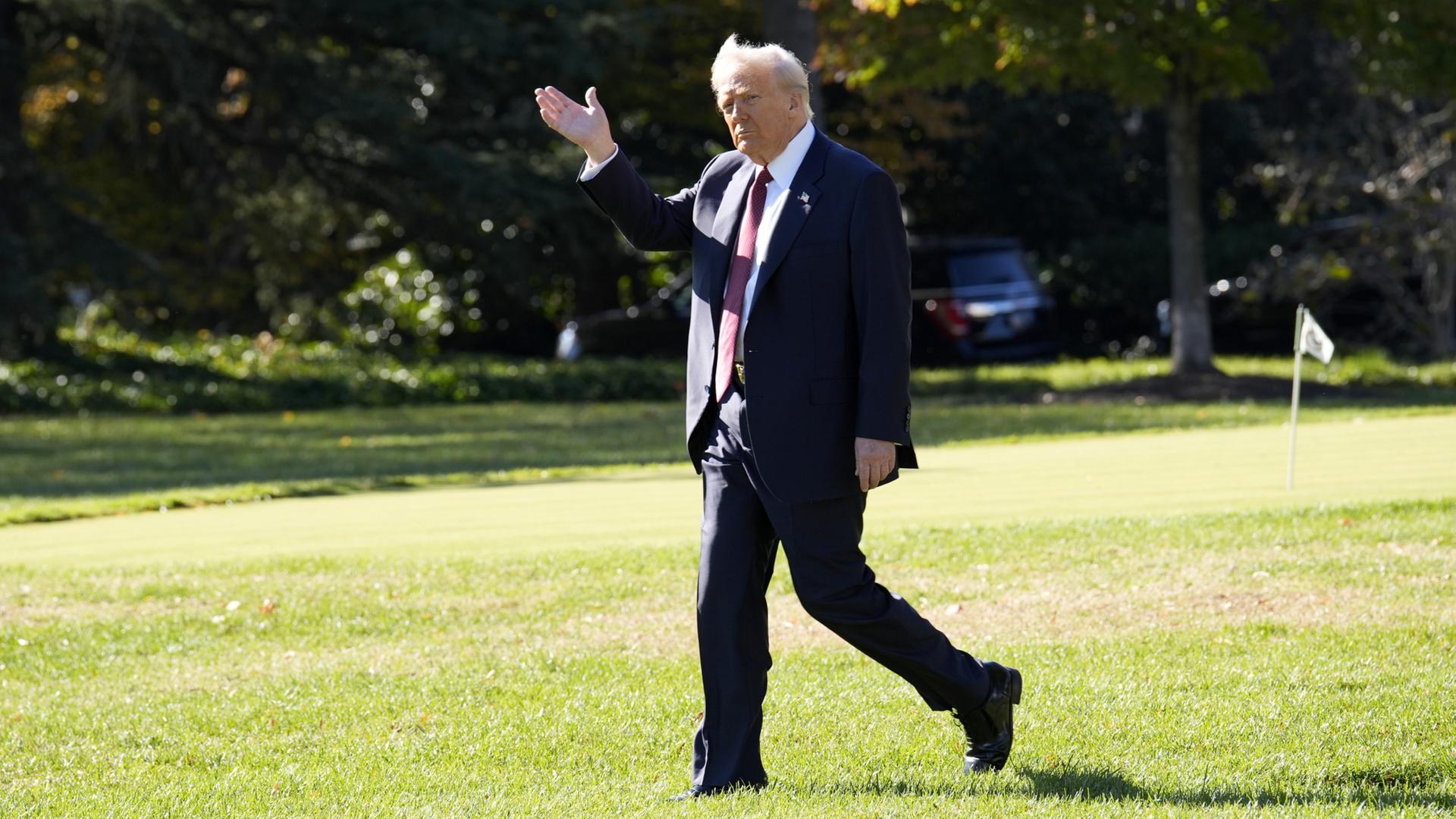 Donald Trump geht über eine grüne Wiese. | EPA
