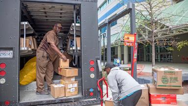 Ein Fahrer von United Parcel Service (UPS) und ein Helfer laden Pakete in einen Paketwagen am New Orleans Convention Center.