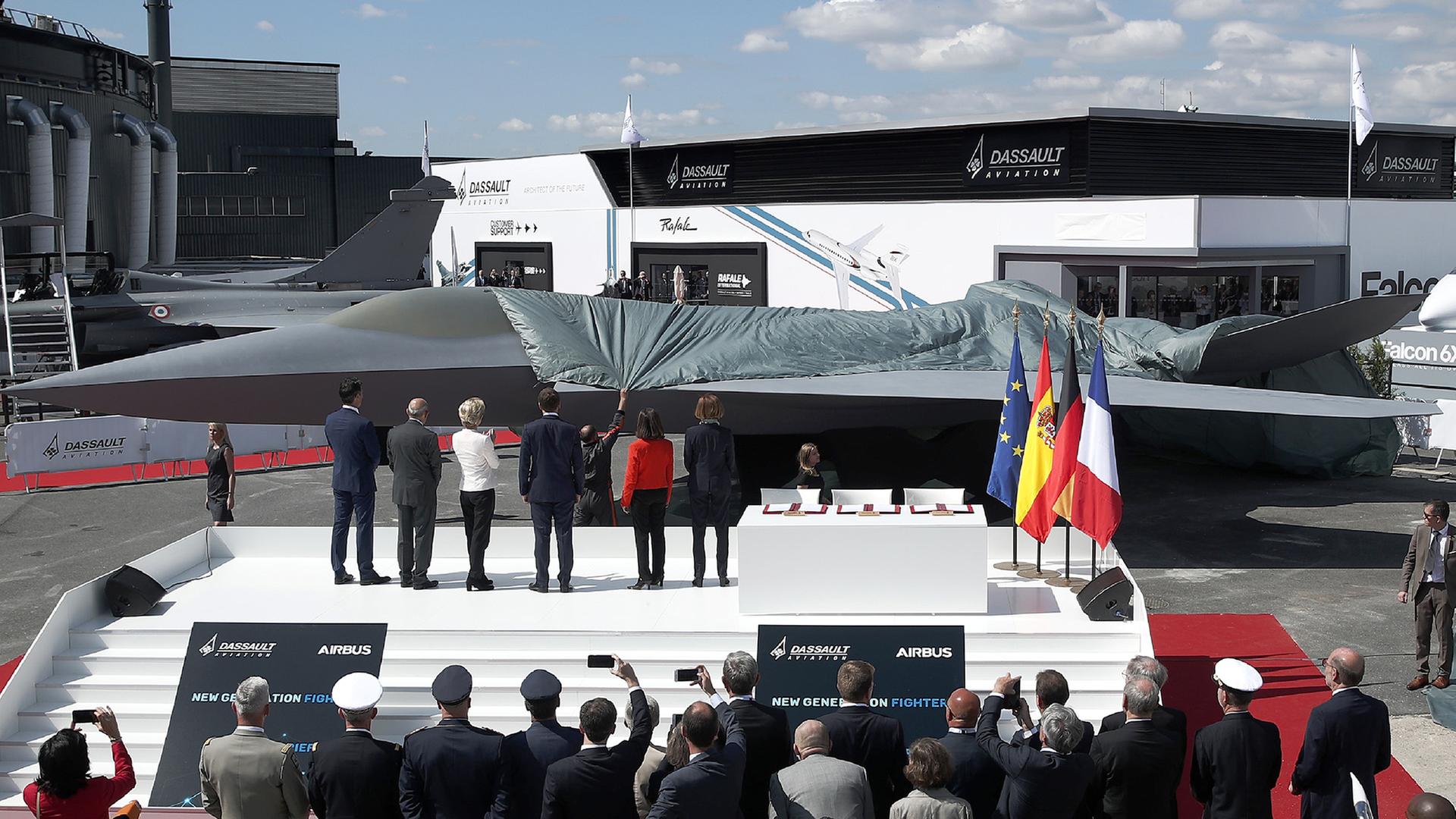 Besucher sehen der Enthüllung eines Modells des Luftkampfsystems der Zukunft (FCAS) auf dem Flughafen Le Bourget zu. | dpa
