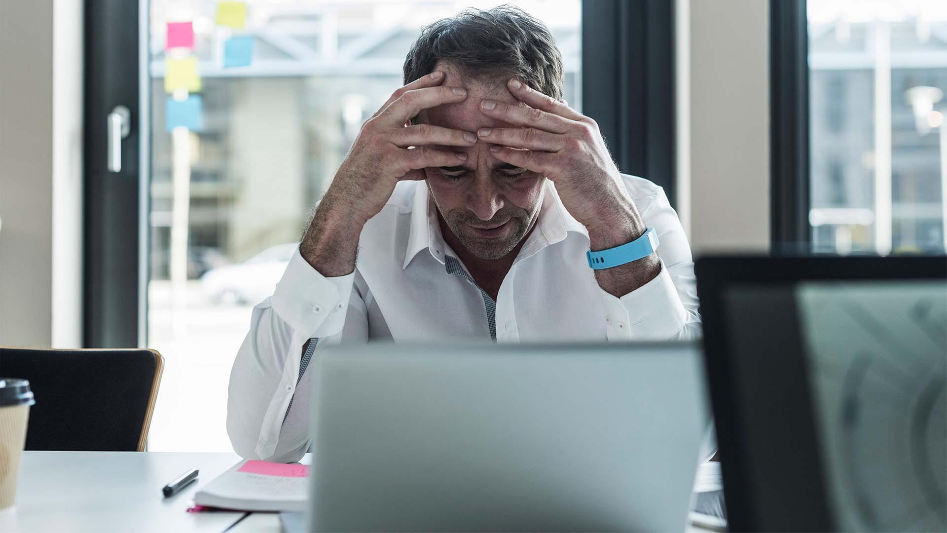 Erschöpfter Geschäftsmann in einem Büro vor einem Computer sitzend. | picture alliance / Westend61