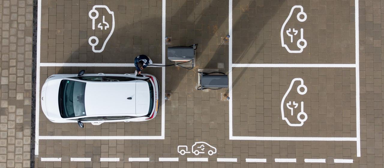 Ein E-Auto steht allein auf einem Parkplatz mit Ladesäulen