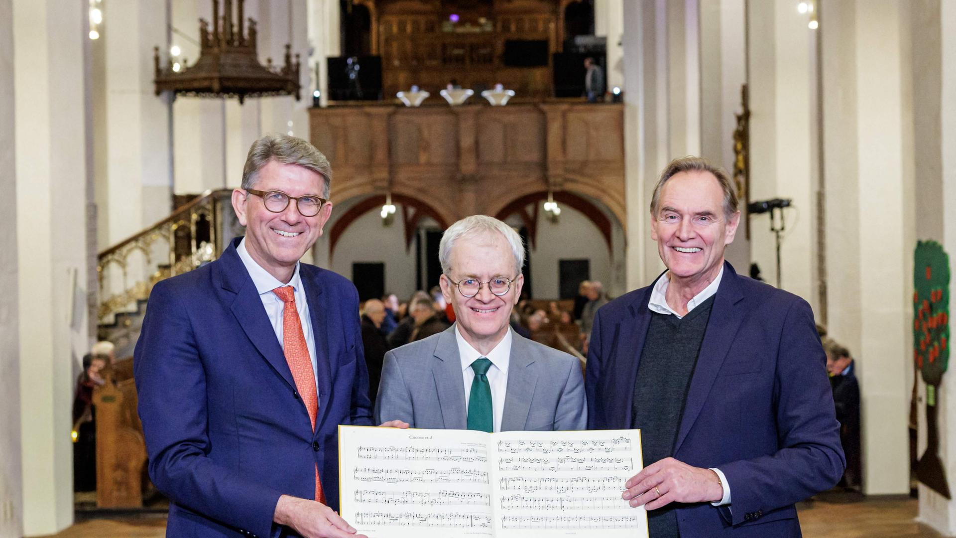 Wolfram Weimer, Peter Wollny und Burkhard Jung mit Noten von Johann Sebastian Bach. | AFP PHOTO /JENS SCHLUETER/BACH ARCHIVE