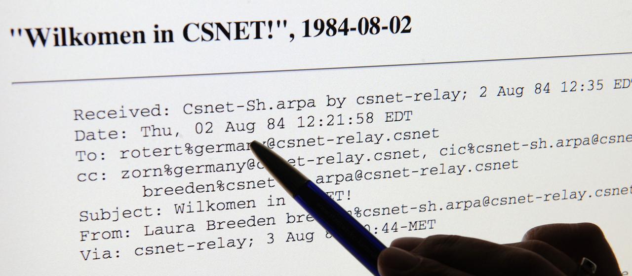 Eine Hand zeigt auf einem Computerbildschirm auf die erste E-Mail in Deutschland.