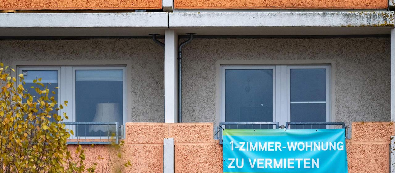 "1-Zimmer-Wohnung zu vermieten" steht auf einer Plane, die an einem Balkon-Geländer in einem Wohngebiet in Neustrelitz angebracht ist.