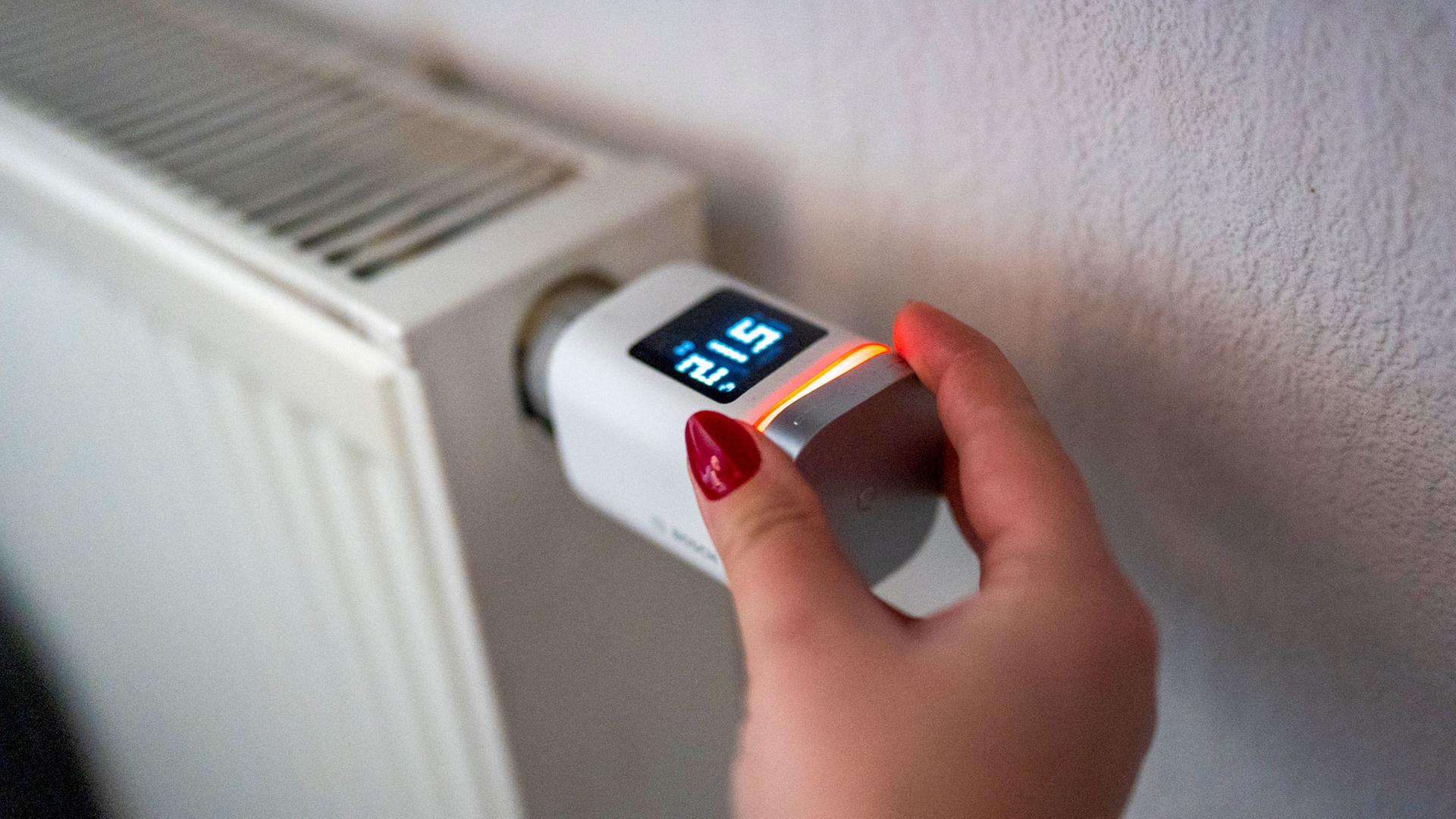 Eine Hand stellt an einem smarten Thermostaten die Temperatur ein. | picture alliance / HMB Media