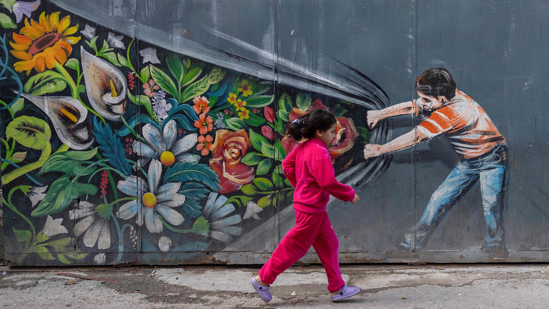 Ein Kind rennt an einem WandgemÃ¤lde im Stadtteil Silwan in Ostjerusalem vorbei. | AFP