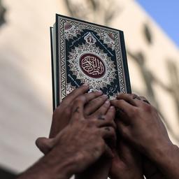 Mehrere Hände halten eine Koran-Kopie in die Höhe - während Protesten in Bagdad