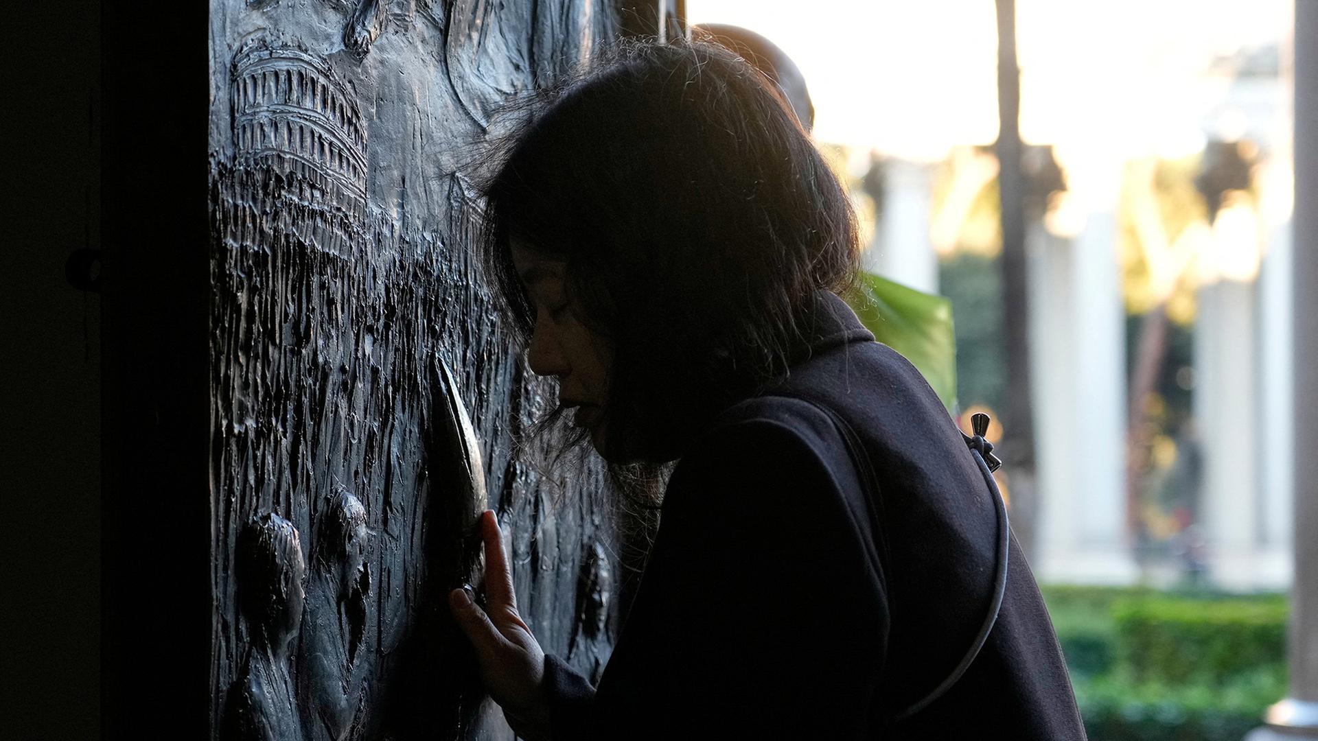 Ein Pilger berÃ¼hrt die Heilige Pforte der Basilika St. Paul vor den Mauern in Rom. | via REUTERS