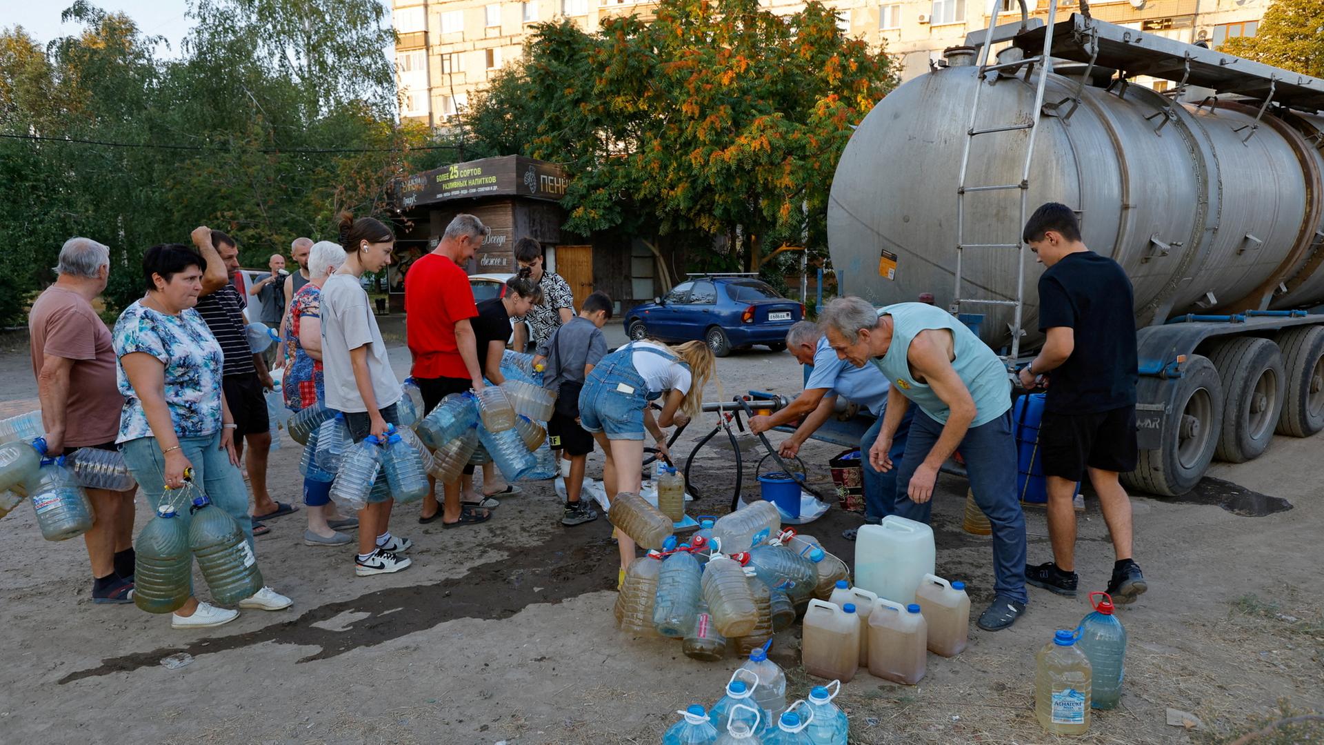 Menschen in Donezk versorgen sich mit Wasser an einem Tanklaster.  | REUTERS